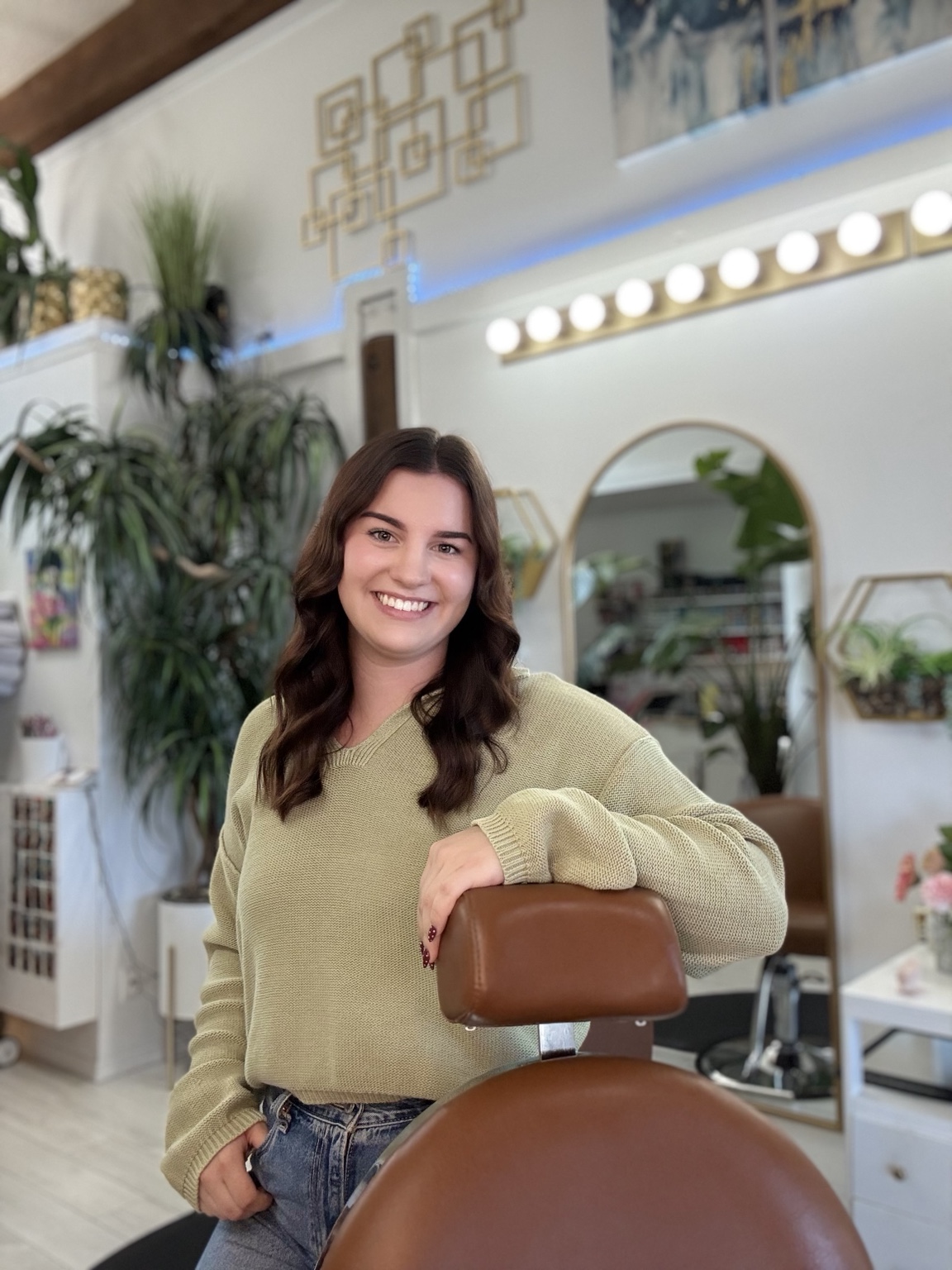 Mackenzie smiling beside her salon chair at Hooked Hair